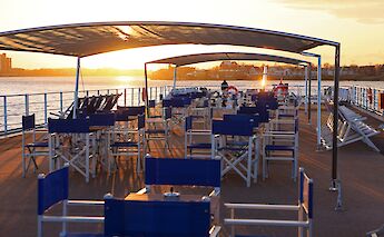 The sun deck of the "Lisabelle" boat at sunset, featuring arranged tables and chairs&hellip;