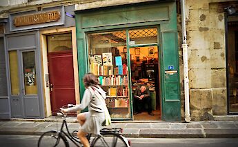 Cycling past a bookshop, Paris, France. Craig Finlay@Flickr