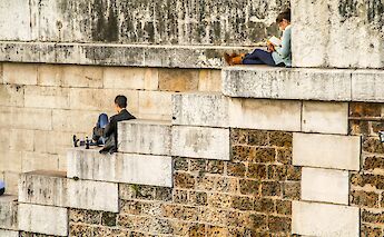 People reading on ancient walls, Paris, France. Viktor Kiryanov@Unsplash