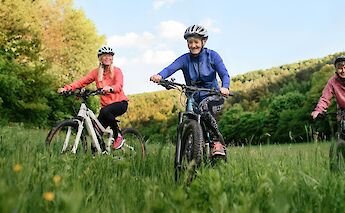 Three women cycling through a field. Getty Images@Unsplash
