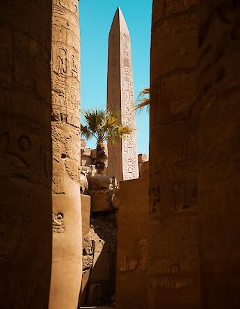 An ancient obelisk framed by temple walls. CharlesEscat@unsplash