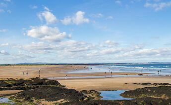 Walkers on the beach, St Andrews. Unsplash@Kirsten Drew