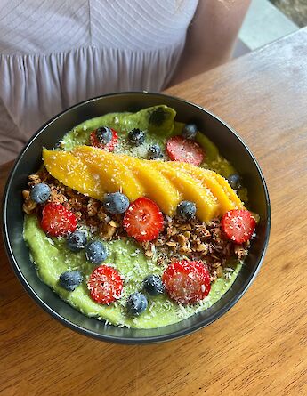 Fresh smoothie bowl topped with tropical fruit and berries. cc-Heather