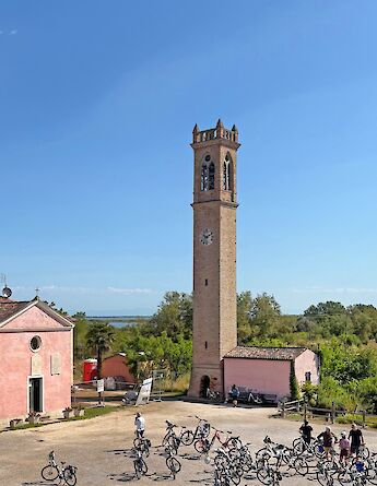 Cyclists gathered near a historic bell tower. toGL